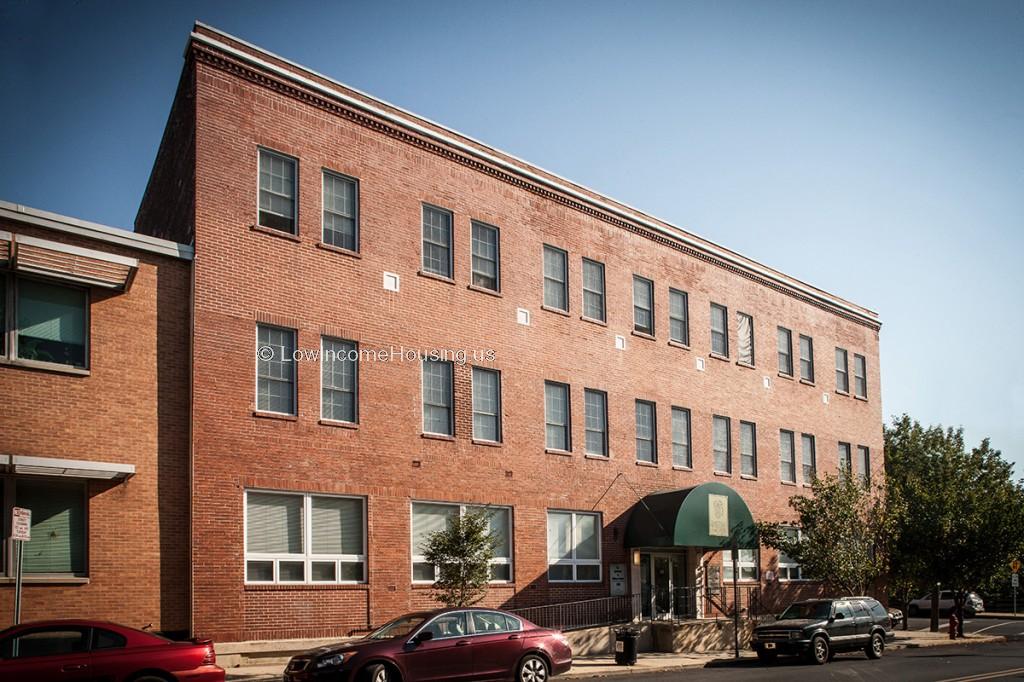 Large, red brick three story apartment building with 18 apartments per floor. Ground floor with large double sized picture windows.  Convenient curbside parking is available for residents.