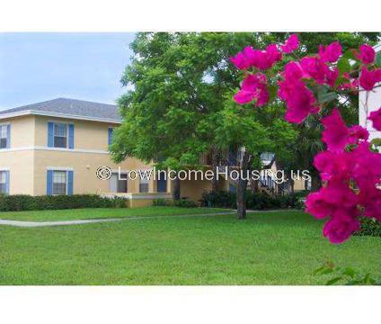 Pink brick townhouse with large shuttered picture windows, air conditioning units, luxuriant foliage  