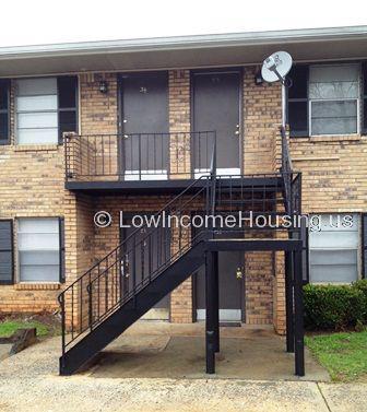 Two story row house with mixed finish red brick, Large windows and external  iron stairwell with railing