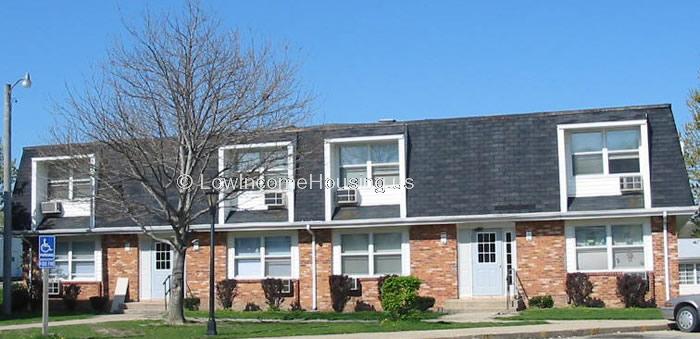 Classic red brick row house with two units.  Each unit has a large, floor to ceiling window with air conditioning unit installed.