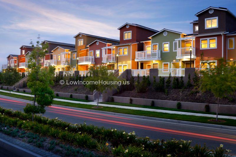 Large three story red brick row houses with balconies and street lighting and elegant dormer windows