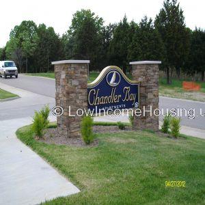 Roadside sign of Chandler Bay Development. A sidewalk and some grass.