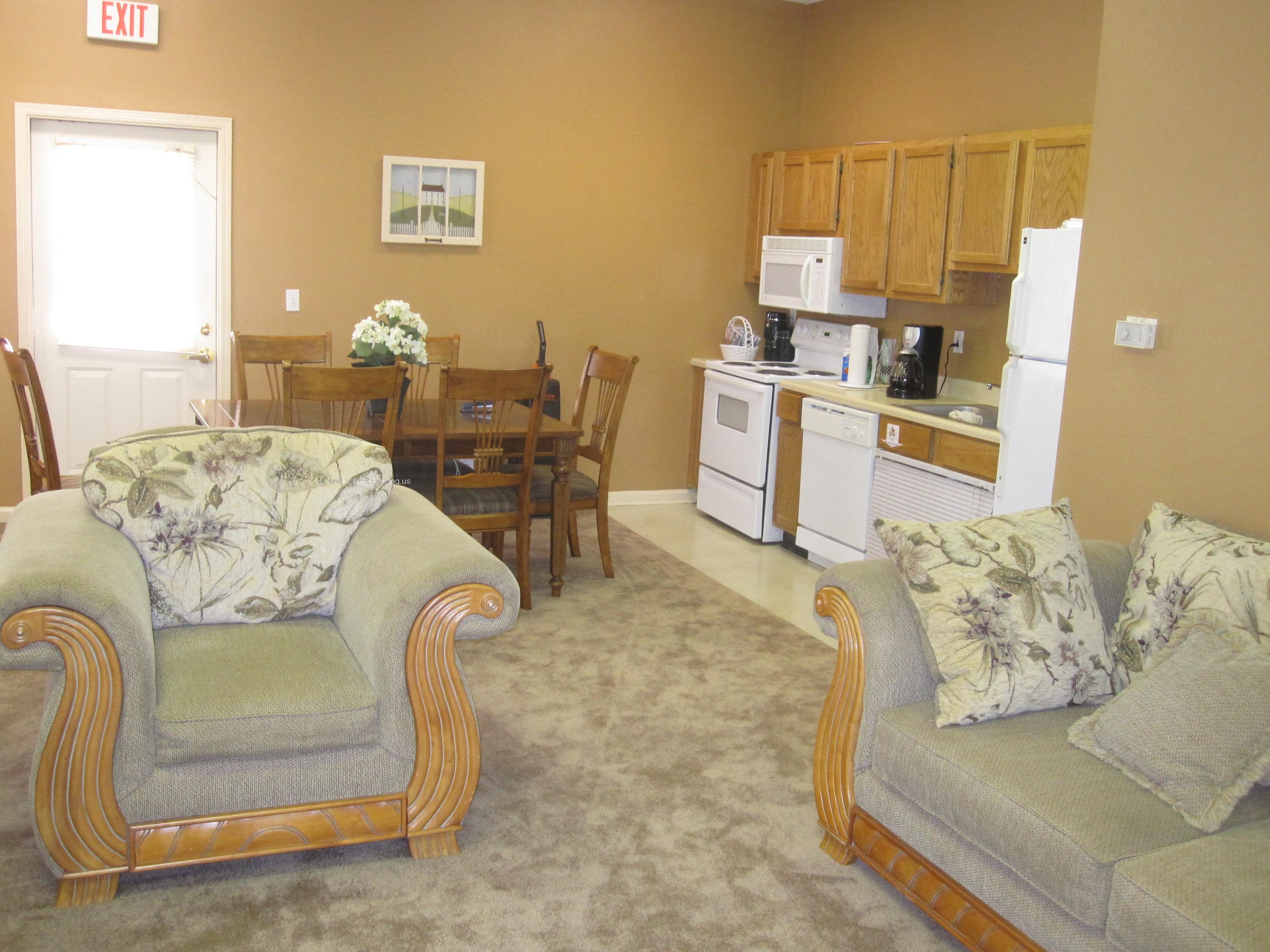 Large, stuffed lounge chair in living/dining area entrance door with bright louvered sun screen.