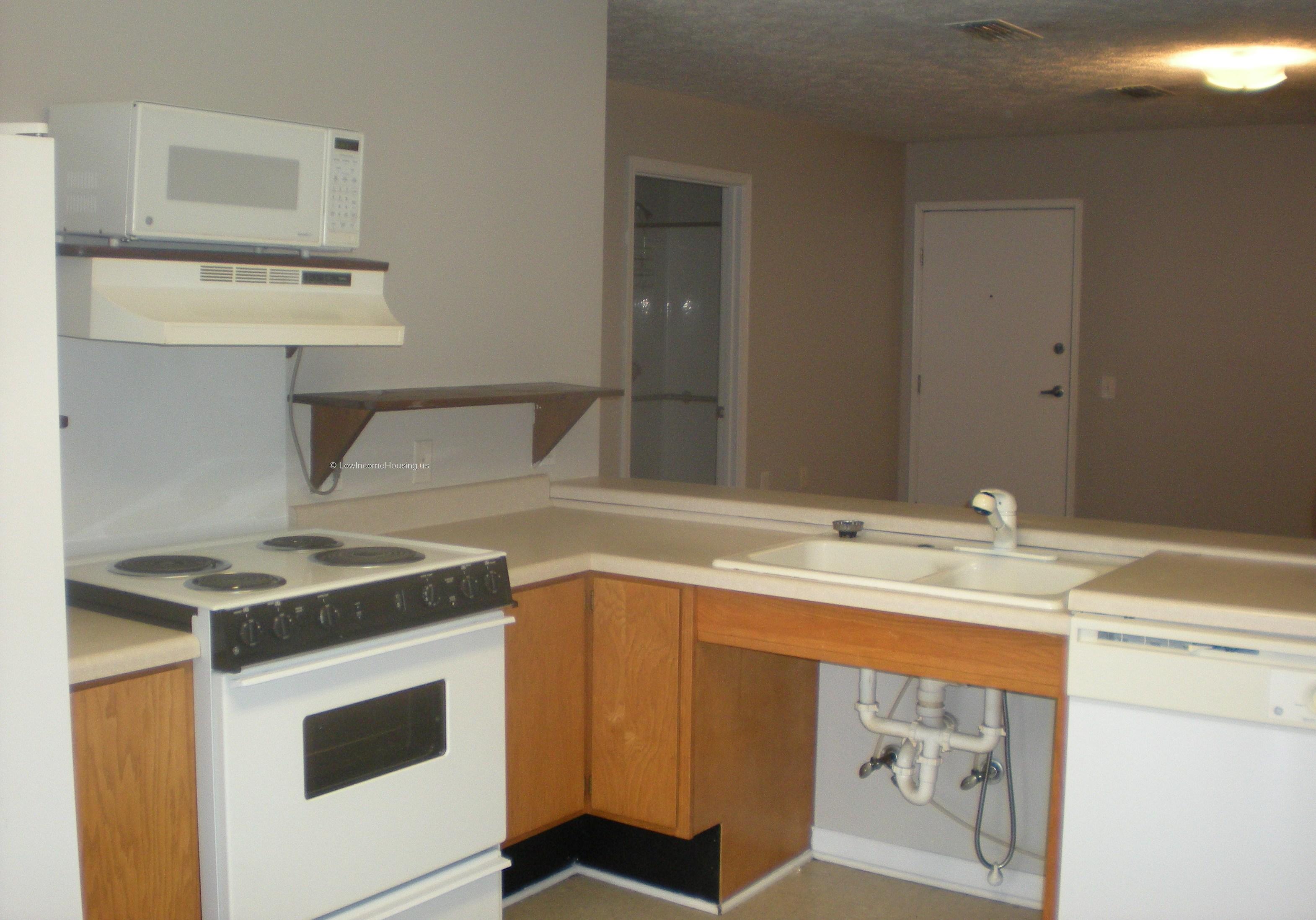 Interior view of kitchen, electric stove top, exhaust unit and twin sinks with hot and cold running water. 