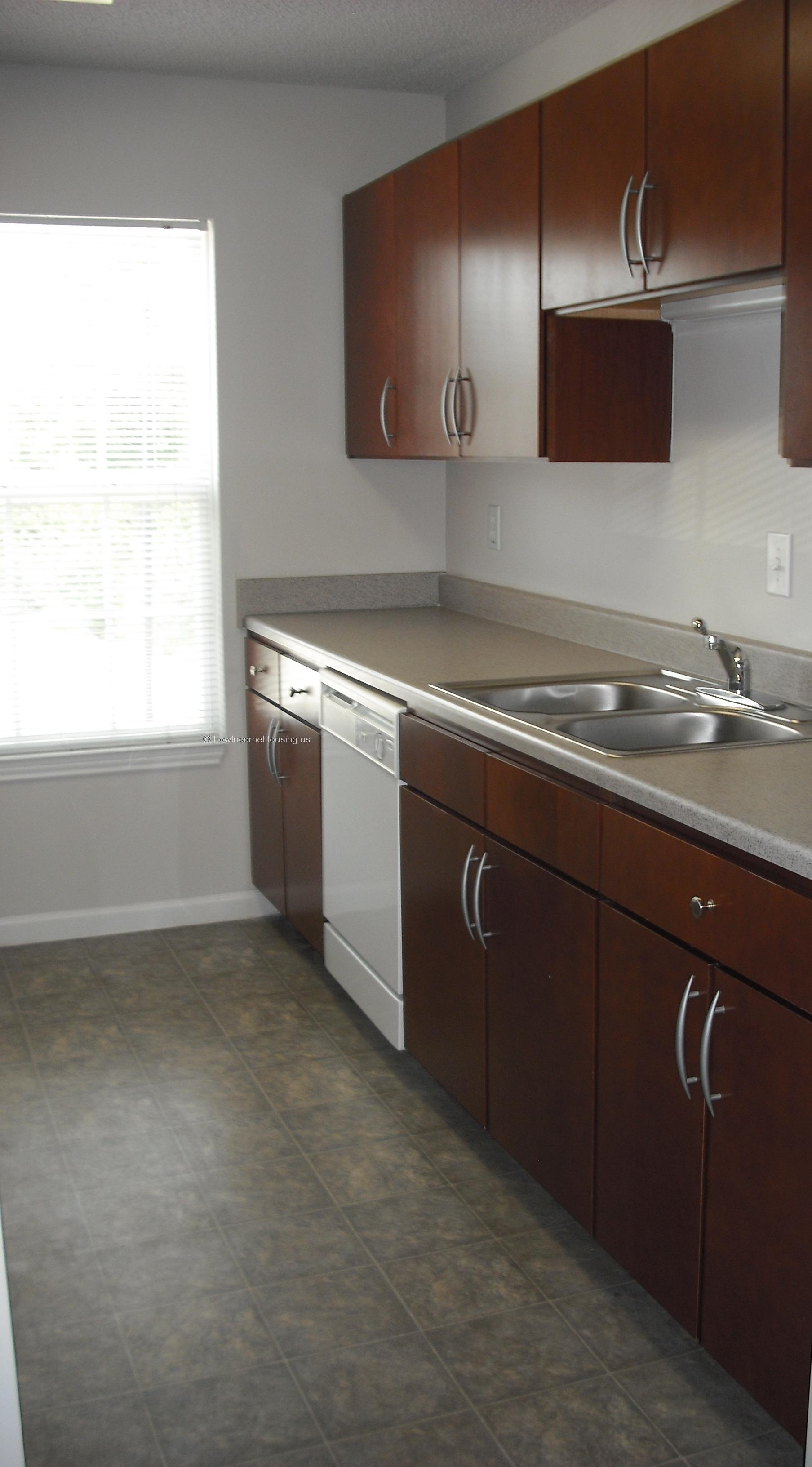Interior of kitchen unit with dishwasher installed, dual basin sinks and large picture window.