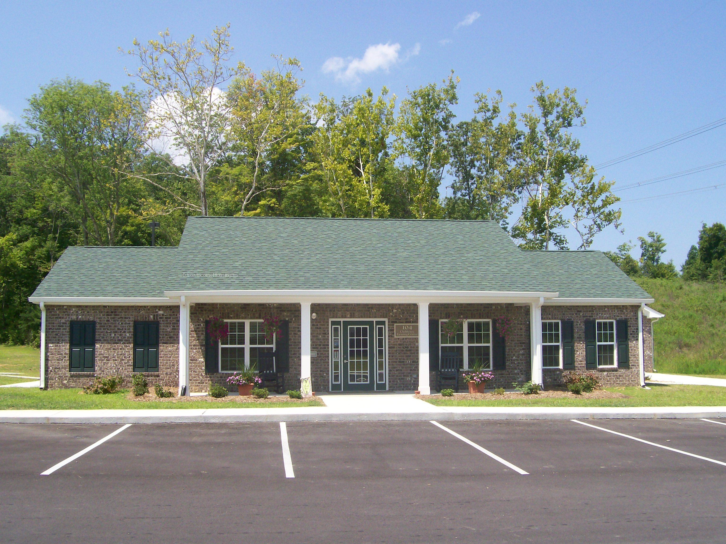 Clubhouse and Learning Center with large windows with exterior shutters and curbside parking.