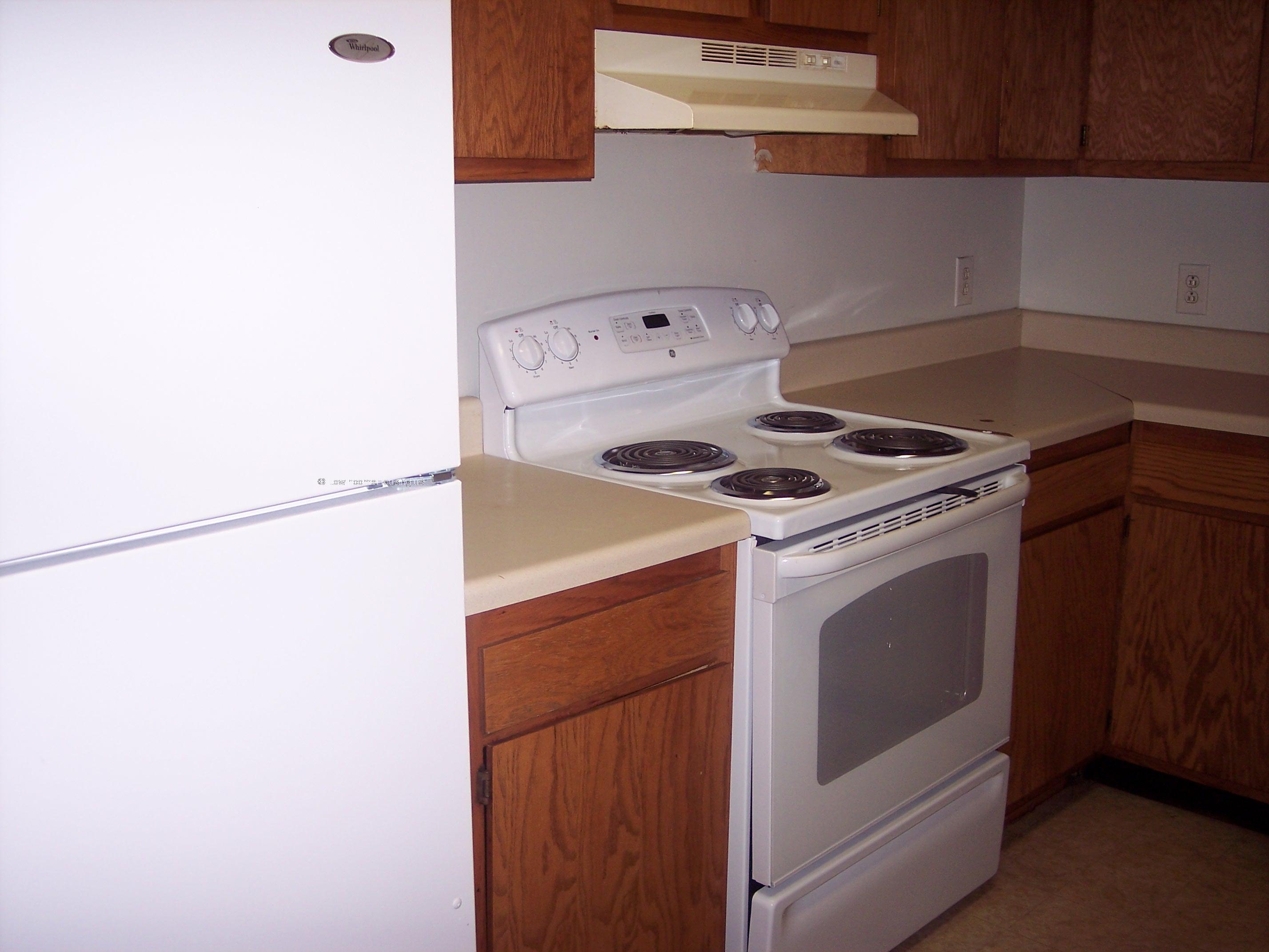 Kitchen equipped with electric range with four heating units, oven with broiler , and overhead exhaust fan. 