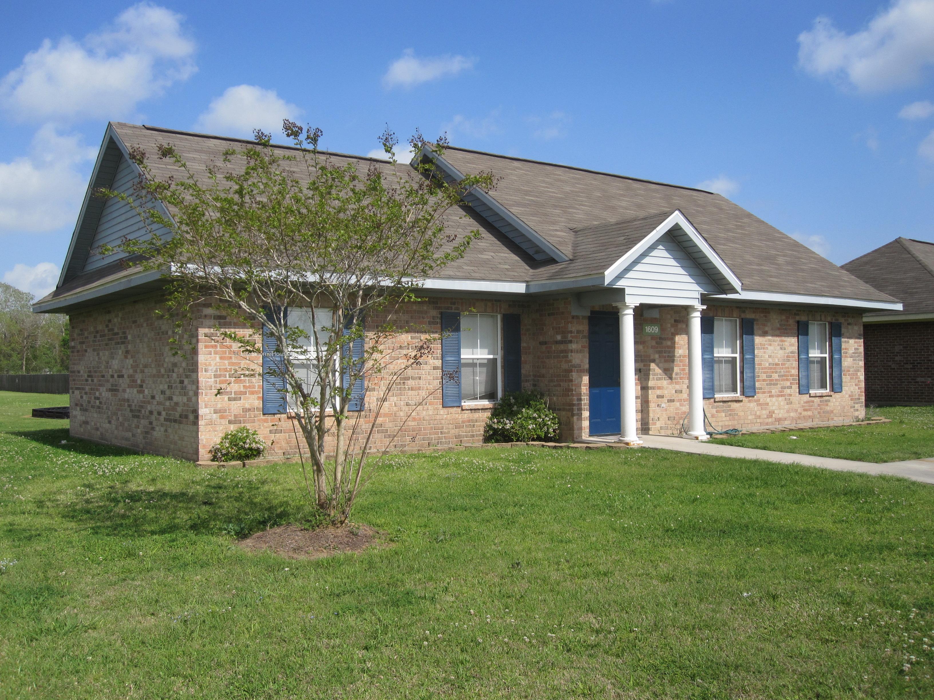 Classic red brick row housing with ample windows and mature foliage.  