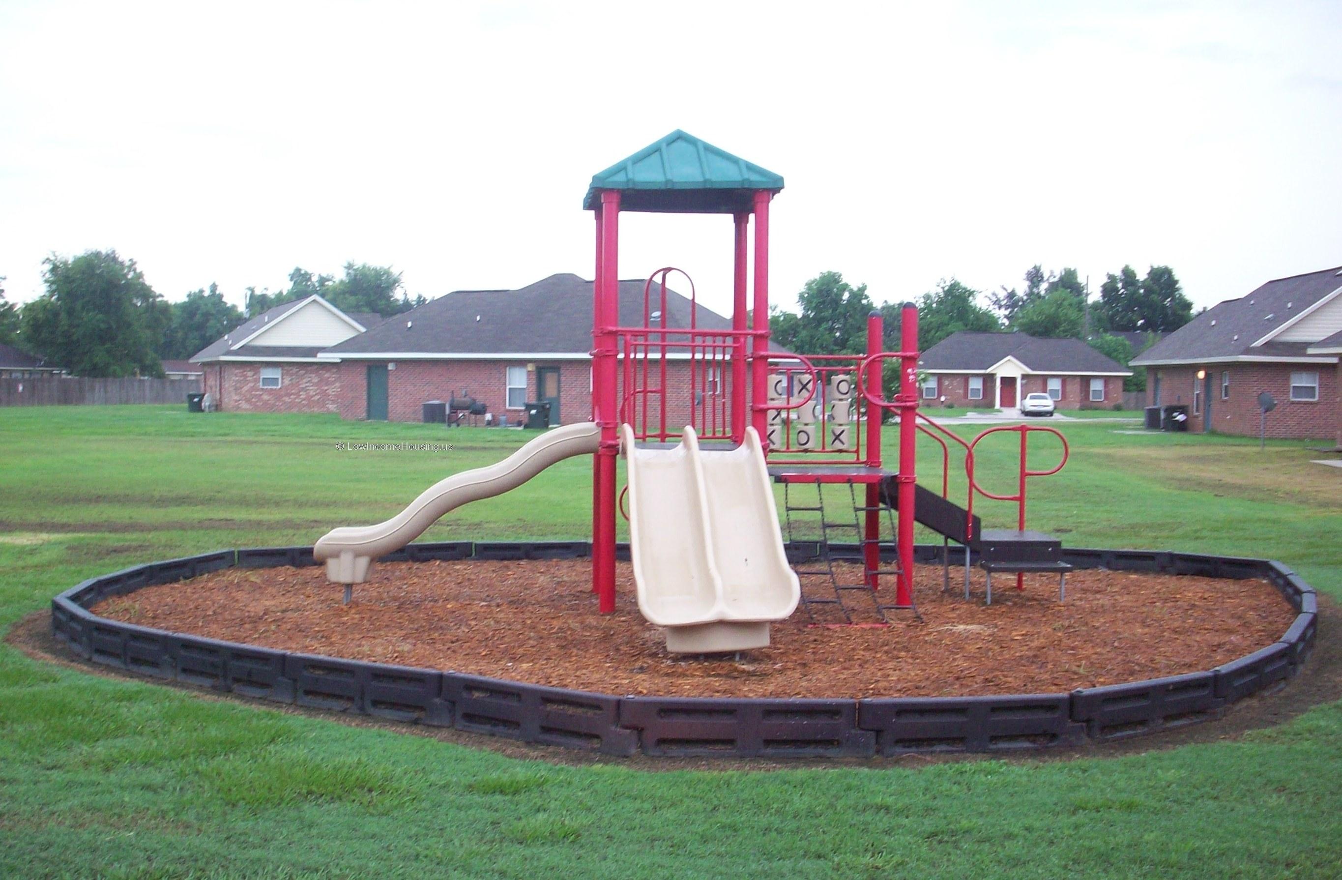 Classic red brick low income housing with exterior air conditioning equipment and manicured play area. 