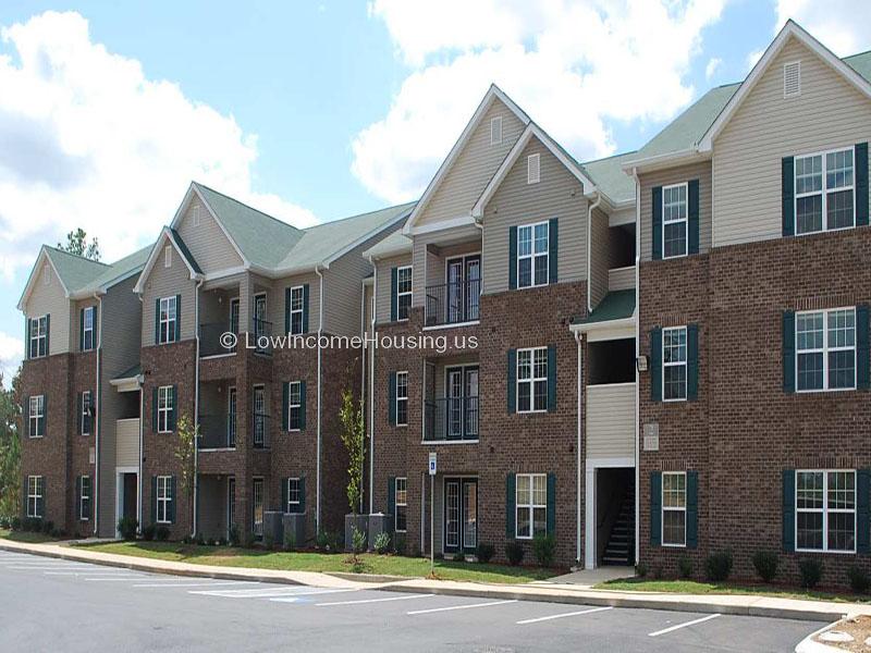 Classic red brick row housing with large, floor to ceiling window units, curb side parking. 