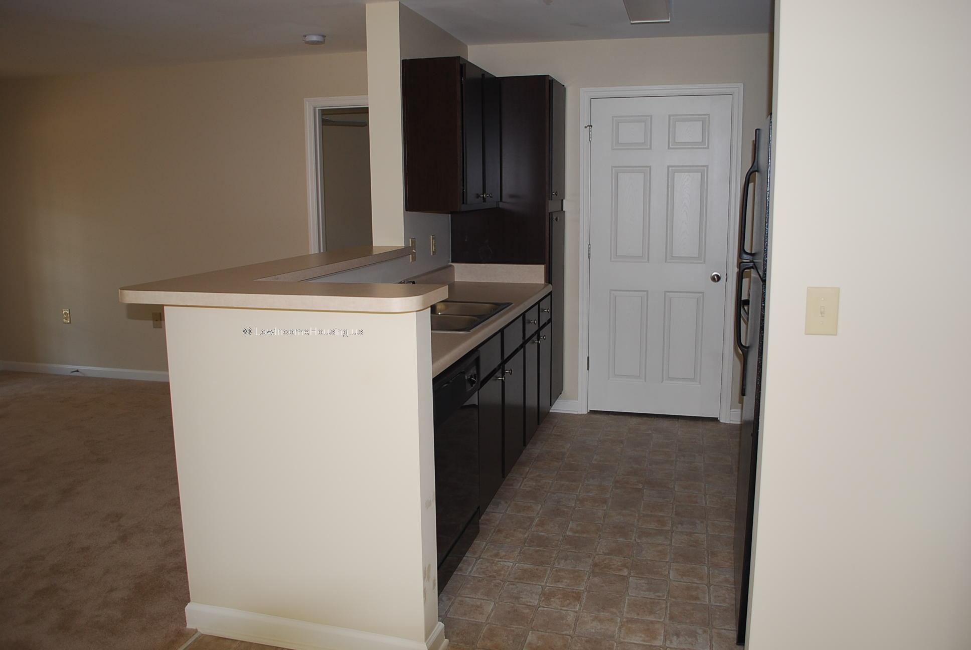 Interior view of dining area and kitchen with refrigerator and storage cabinet. 