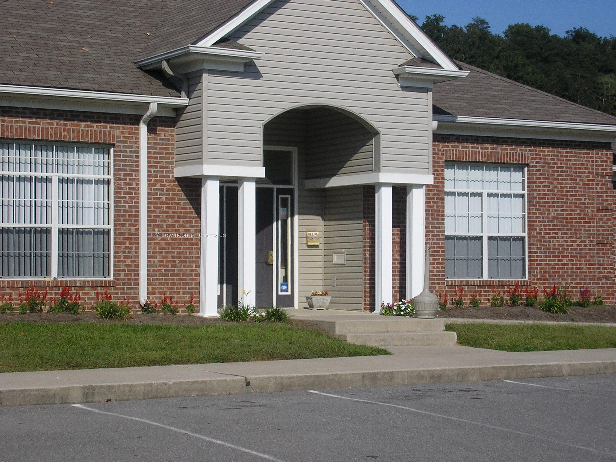 Classic red brick row house construction with two large dormer winnows, patio style parking space  