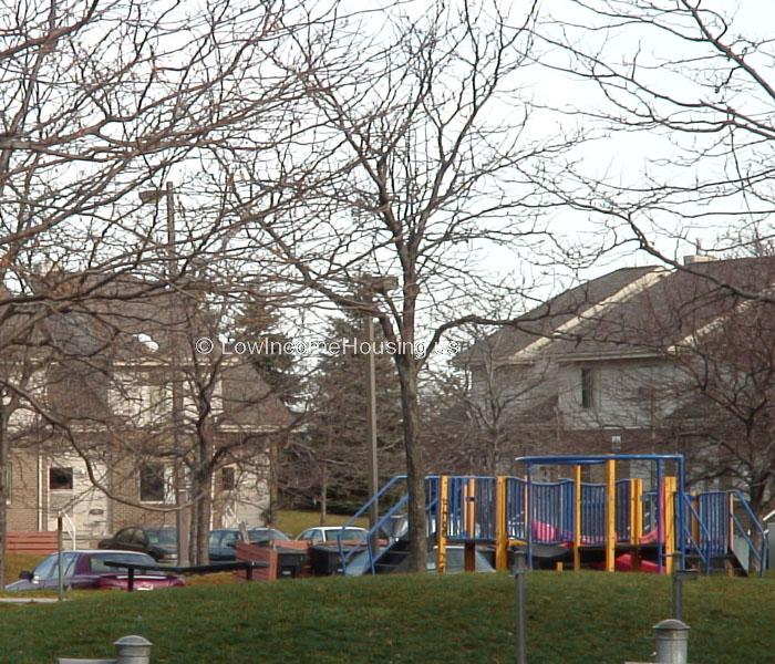 Elegant wooden construction of family living units and second level dormers.  Large Play area for children with jungle jim, sliding board, and seating area for adults.