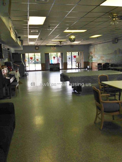 Photo graph of large foyer with exit to patio area.  Foyer is equipped with saveral large tables and chairs.