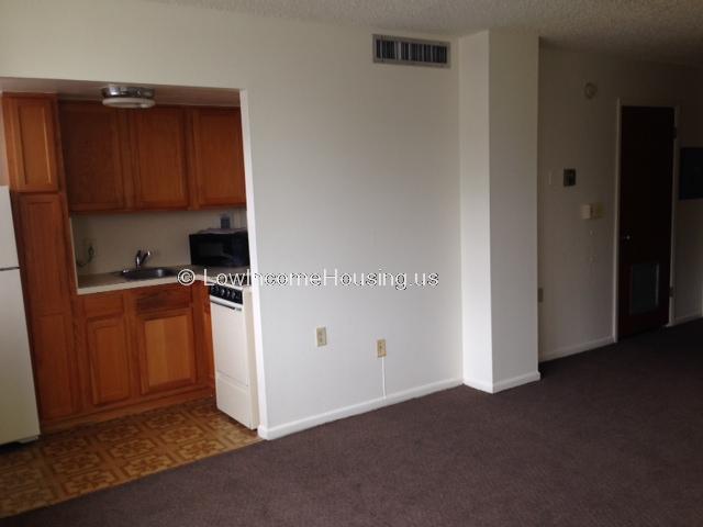 View of kitchen from living area.  Refrigerator door, stove and twin sinks can be seen.