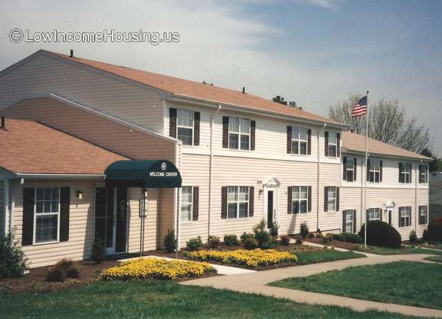 Large centrally located housing unit finish in wooden clapboard.  The first unit on the left is the Welcome Center, The second unit in the middle is the administrative offices and third unit is maint 