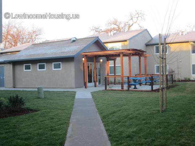 Large single unit housing block with exterior wooden cover over entrance, exterior seating with picnic table.