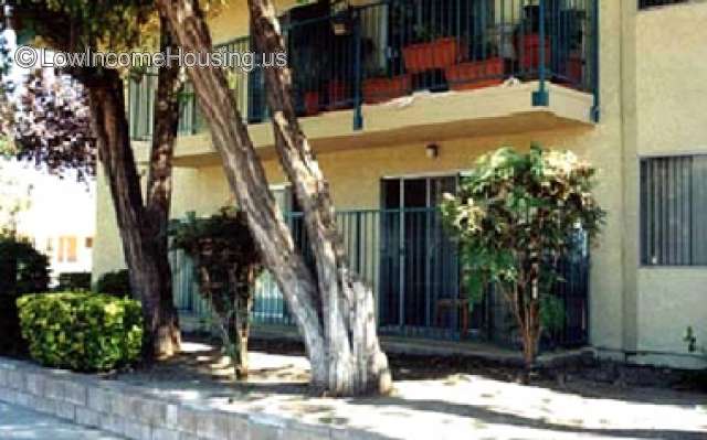 Three story apartment with wrought iron balconies and established shade trees