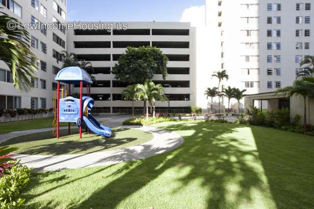Large white apartment building with carefully manicured lawn and plastic coating on jungle gym 