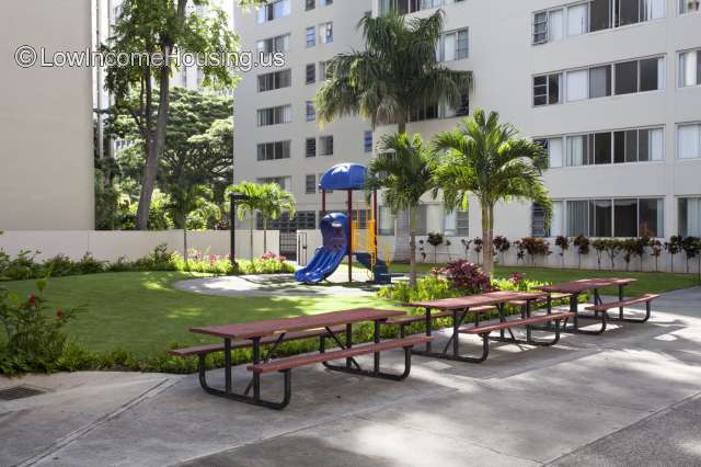 Large multistory apartment building with picnic tables and jungle gym 