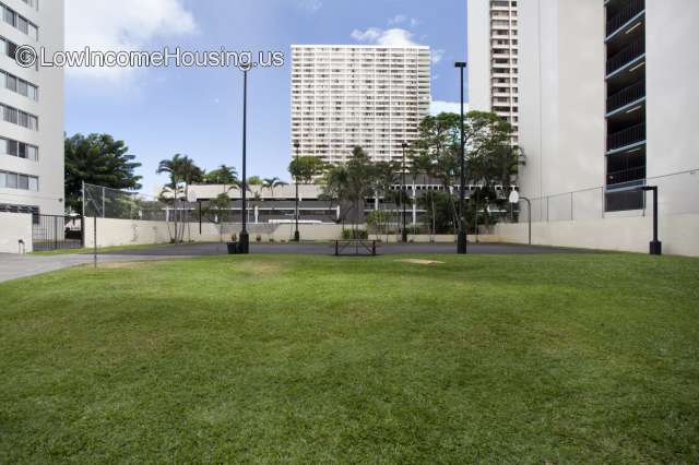 Large, white, multi-storied apartment buildings with exterior seating, ample illumination and assorted gym equipment 