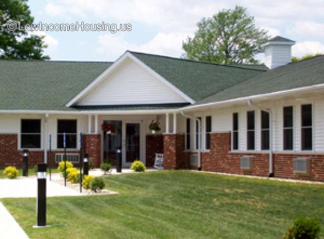 This is the corner unit for a low income housing unit.  It appears to be the office of the management personnel.  The construction is red brick with window air conditioning units. 