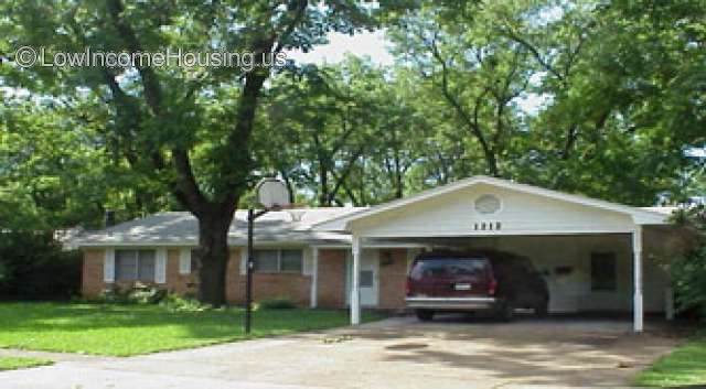 Classic red brick housing unit with floor to ceiling windows installed. Parking space is adjacent for two additional vehicles.