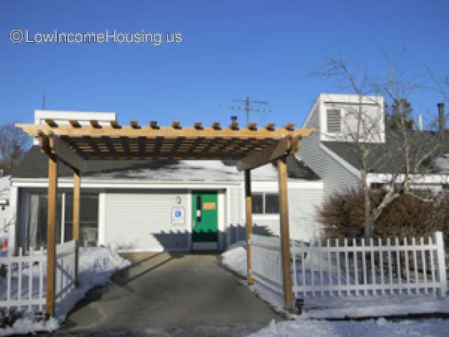 Single story residential property with a pergola and white picket fence. Snow on ground
