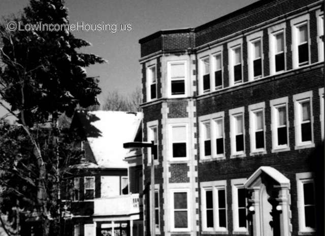 Three story red brick structure with beautiful white concrete trim. Each unit contains four individual dormitory units. 