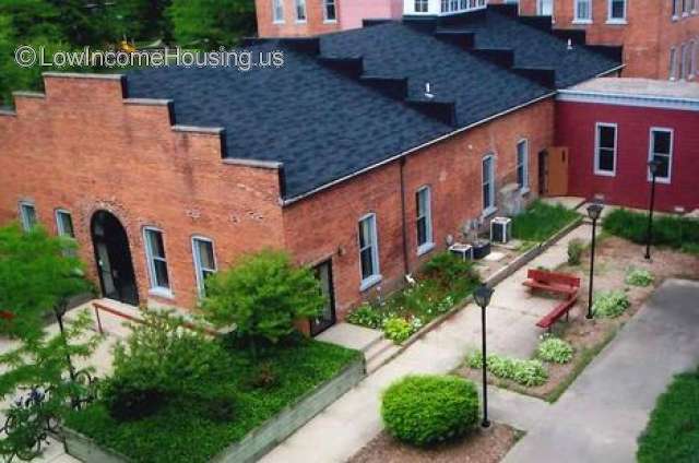 Church constructed of red brick.  Building is very large, there are 10 floor to ceiling windows built into the  exterior wall.  Air conditioning equipment is arrayed outside on the right wall.  