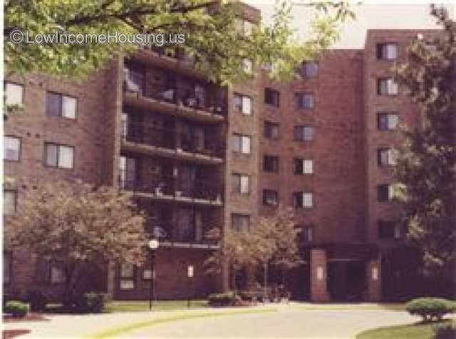 Classic red brick construction for  large apartment complex with exposed balconies equipped with wrought iron fencing. 