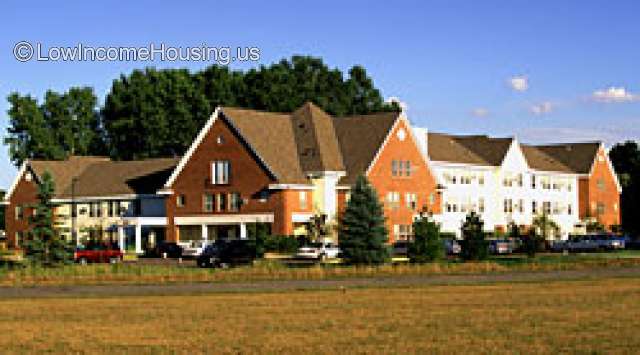 Corner shot of building in the country. Cars parked in front. Three story building.