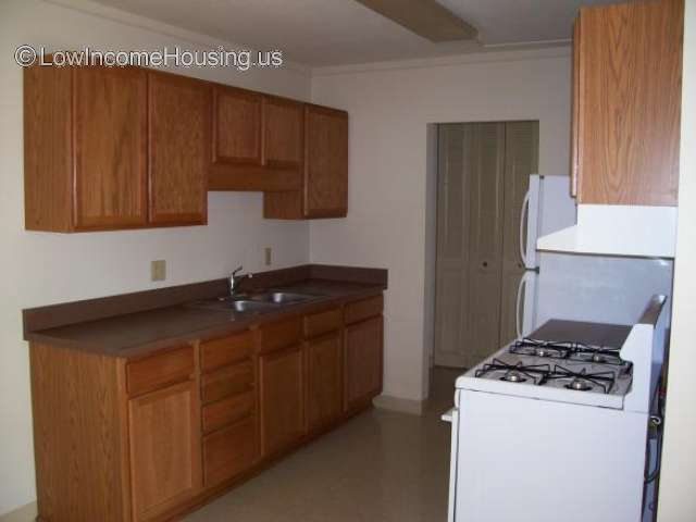 Interior photograph of kitchen interior, gas range/oven, combined refrigerator freezer unit, sink and ample cupboard storage.