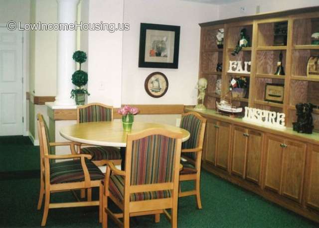 This is a dining area equipped with 4 chairs, a round table, shelves for storing diner ware, plates and sundries.