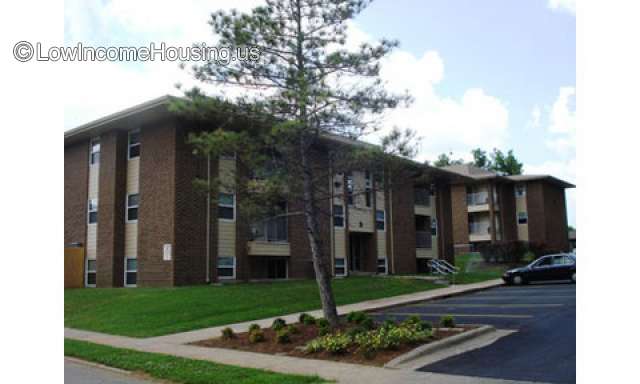 Outdoor picture of driveway in front of 2 story front office building. A palm tree to the right of the building and residential area in the back.