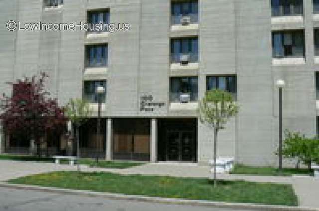 streetview picture  of large gray building at least four stories and some young trees on sidewalk