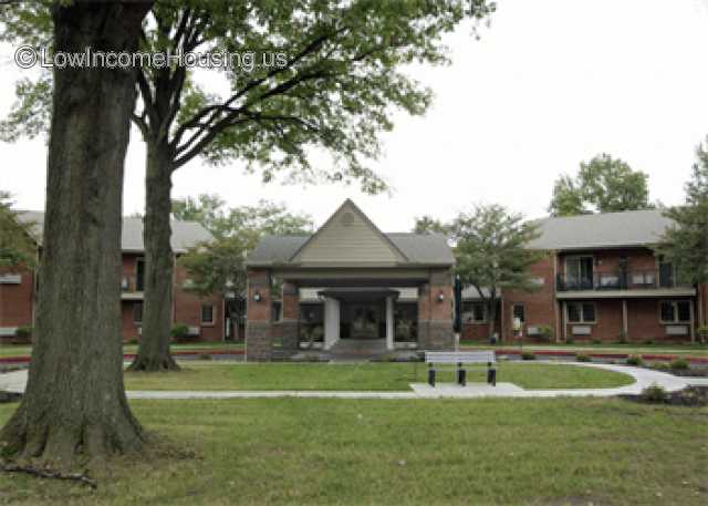 Photograph of a main office building with two white columns flanked by buildings that used a similar construction method.  