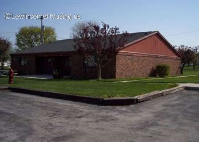 This is a photograph of a red brick building that forms the foundation for a simple wooden roof.