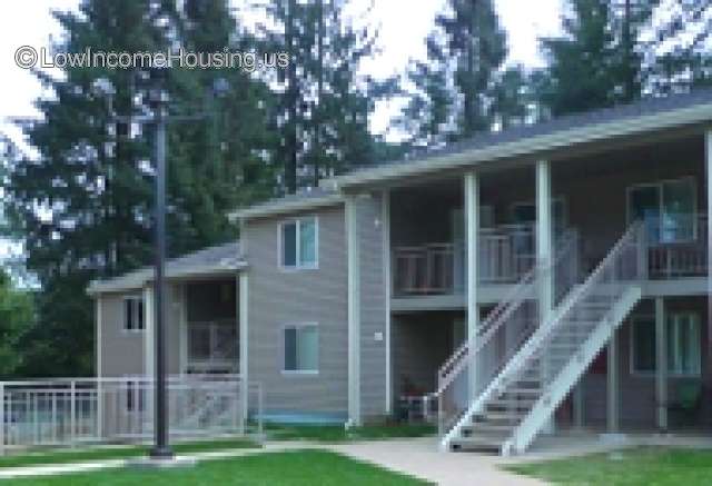 Two Story Grey Clapboard Paneling with exterior stair case leading to second floor. Second floor has wrought iron steel framing. Large windows with view to parking arear. 