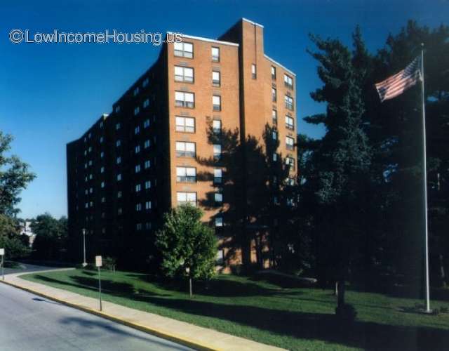 Very Large red brick 9 story building with windows facing street parking.