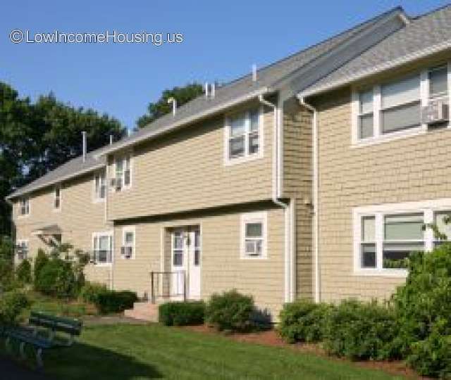 This shows three row houses constructed of wooden framing and painted a light yellow.  Window and door trim are painted white. 