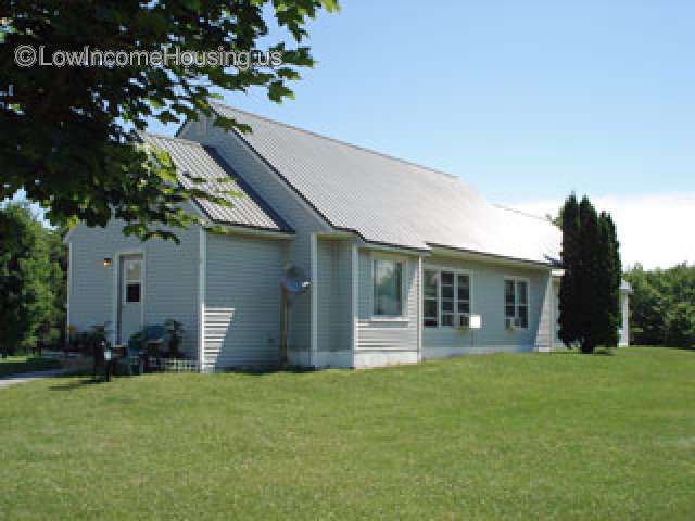 Corner picture of single story house with large grassy area in front.