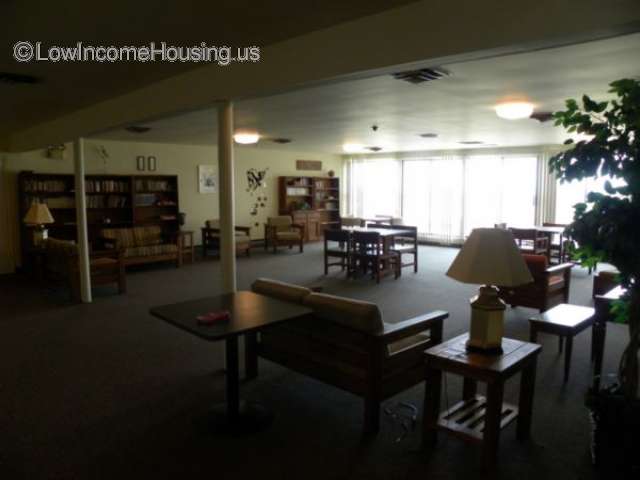 Interior view of large, spacious living and dining area.  Large windows are located on a balcony overlooking beautifully kept foliage and landscaping. 