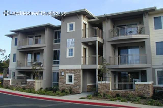 Streetview photo of three story building with balconies. Stone and stucco facade.