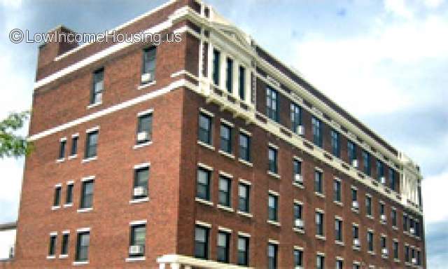 Photograph of 4 story brick building, with 14 windows facing right and  4 windows facing left.