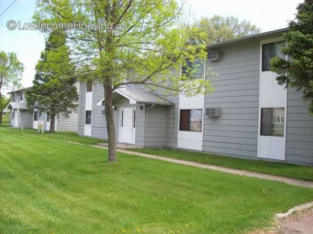 Housing unit painted gray.  There is an entrance door.  On each side of the entrance are 2 windows.  Each window extends up to the second floor.