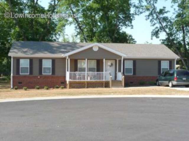 The photograph shows a rectangular structure with two windows on each side.  In the middle are a flight of stairs leading up to a small porch 