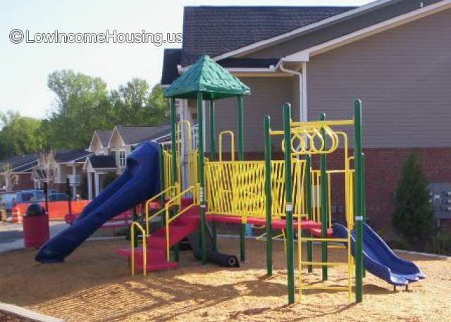This is a photograph of a childs play ground that is equipped with two sliding boards, two fences 