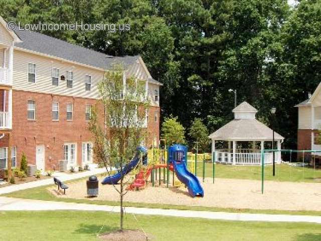 This photograph shows a playground that has been constructed for several children to use simultaneously: two sliding boards, a ladder and a bench.