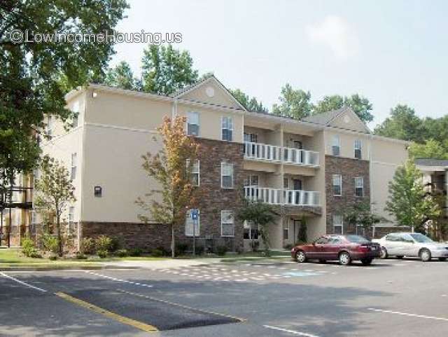 This photo shows the entrance to Scotts Crossing Apartments.  There are three floors (ground and 2 upper floors) and two windows on each side of the entrance. 